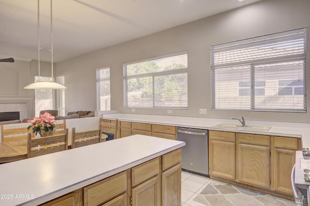 kitchen featuring a tile fireplace, sink, hanging light fixtures, stainless steel dishwasher, and light tile patterned floors