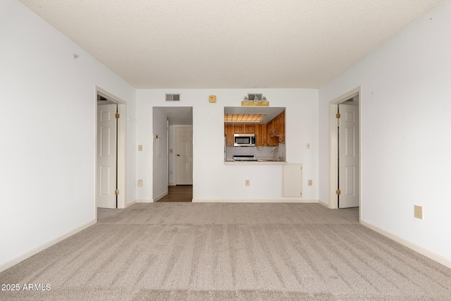 unfurnished living room with sink, light colored carpet, and a textured ceiling