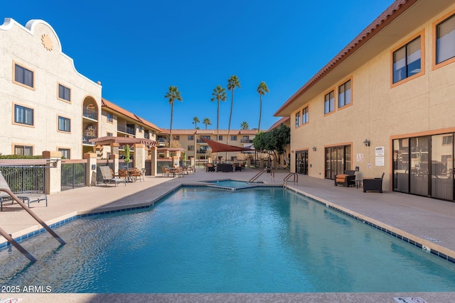 view of swimming pool with a hot tub and a patio