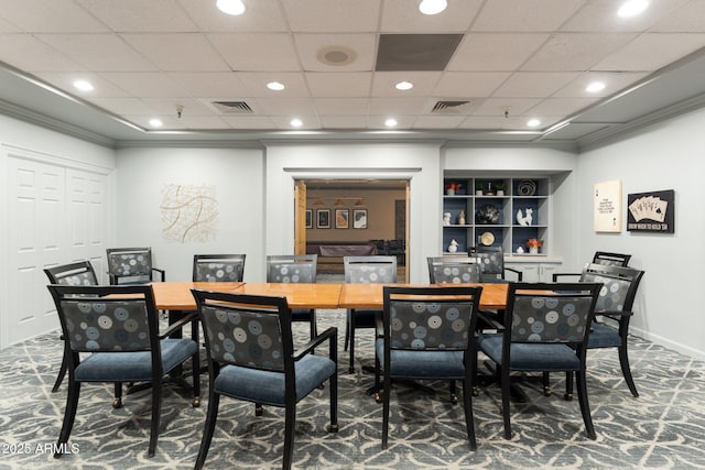 dining area featuring carpet floors, a drop ceiling, and built in shelves