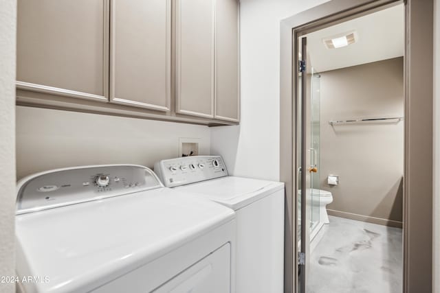 clothes washing area featuring cabinets and washing machine and clothes dryer