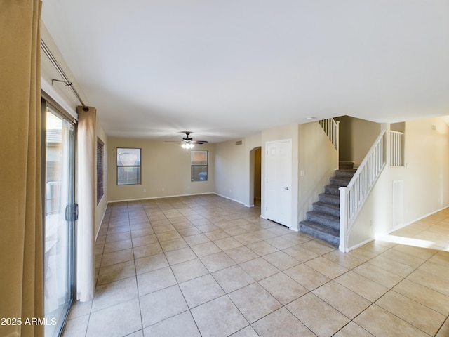 8022 S 48th Dr, Laveen, AZ 85339 - unfurnished living room with light tile patterned flooring, arched walkways, stairway, a ceiling fan, and baseboards