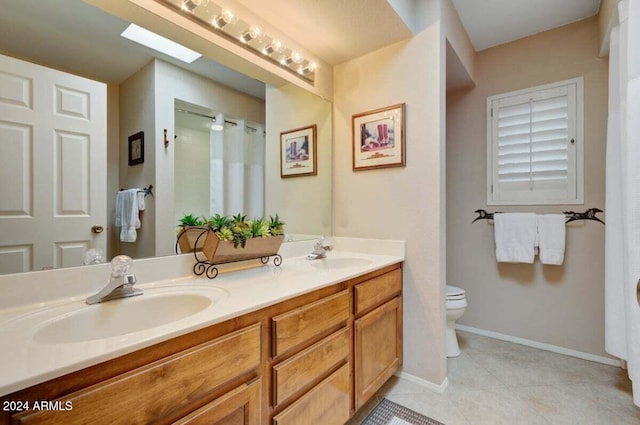 bathroom with a skylight, tile patterned flooring, vanity, and toilet