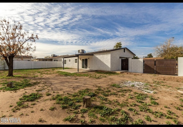 rear view of property featuring stucco siding, a gate, fence, and a patio area
