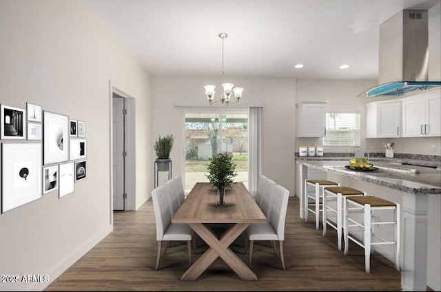 dining room featuring wood tiled floor, a healthy amount of sunlight, and a notable chandelier