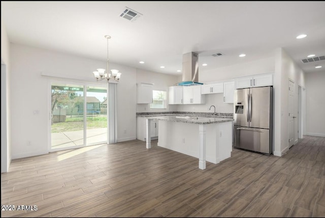kitchen with white cabinetry, visible vents, stainless steel fridge, and an inviting chandelier