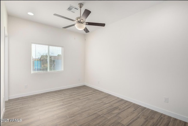 spare room with a ceiling fan, wood finished floors, baseboards, and visible vents
