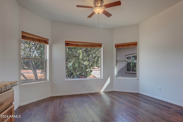 spare room with dark wood-type flooring, ceiling fan, and a healthy amount of sunlight