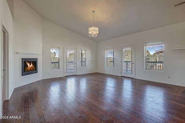 unfurnished living room featuring a notable chandelier, dark wood-type flooring, and high vaulted ceiling