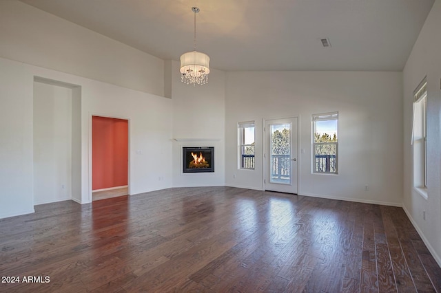 unfurnished living room featuring high vaulted ceiling, a notable chandelier, and dark hardwood / wood-style flooring