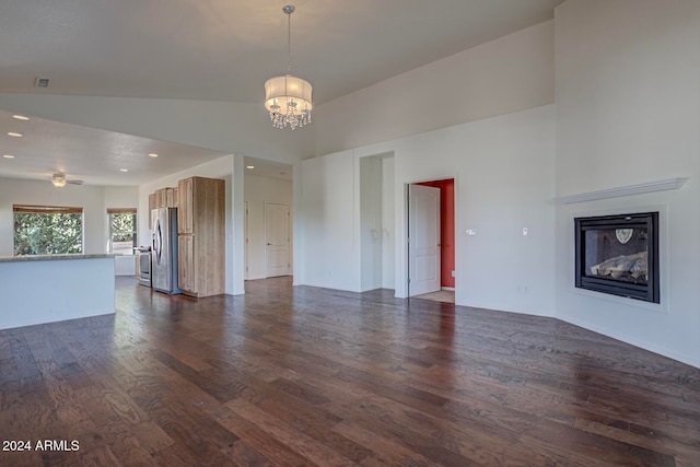 unfurnished living room featuring dark hardwood / wood-style flooring, a chandelier, and high vaulted ceiling