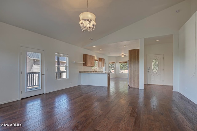 unfurnished living room featuring lofted ceiling, dark hardwood / wood-style flooring, and ceiling fan with notable chandelier