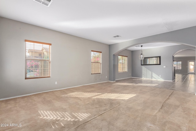 spare room featuring light colored carpet and an inviting chandelier