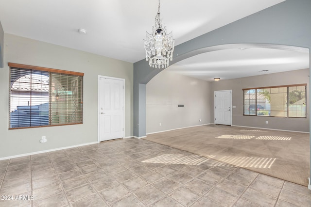 unfurnished room featuring light carpet and a notable chandelier