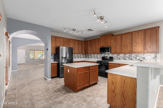 kitchen featuring stainless steel appliances, light tile patterned floors, tasteful backsplash, and a center island