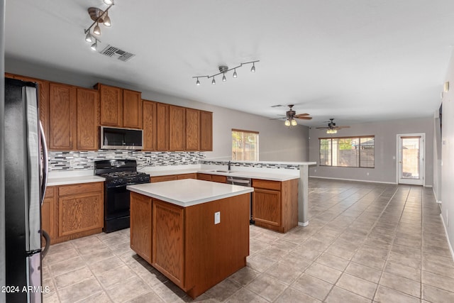 kitchen with tasteful backsplash, a center island, sink, stainless steel appliances, and light tile patterned floors