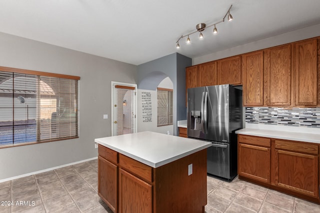 kitchen with decorative backsplash, light tile patterned floors, stainless steel fridge with ice dispenser, and a center island