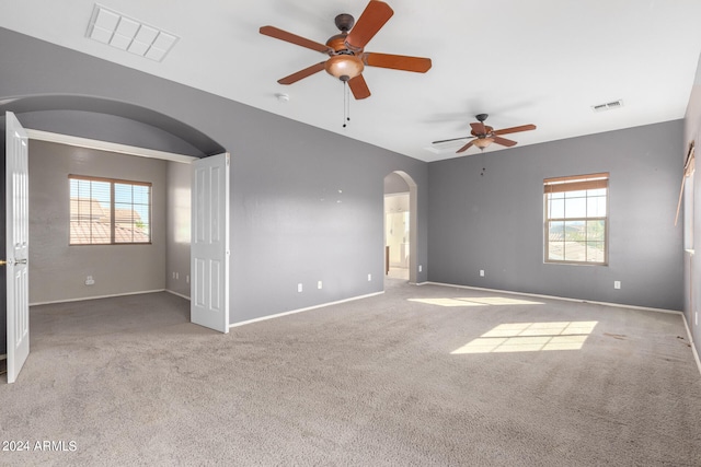 empty room featuring ceiling fan, light carpet, and a wealth of natural light