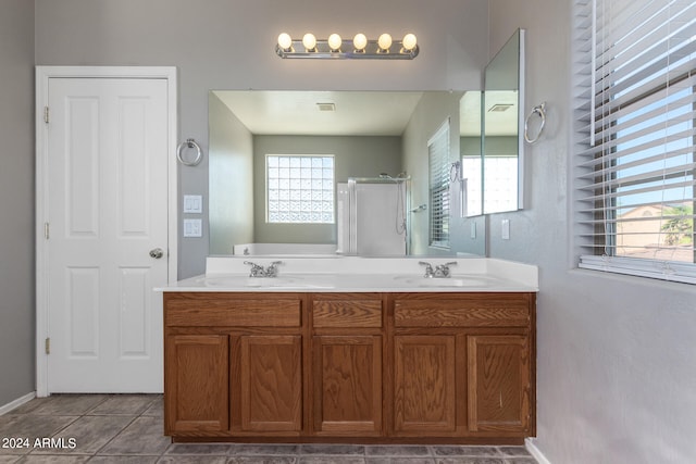 bathroom with tile patterned flooring, a shower with shower door, vanity, and a healthy amount of sunlight