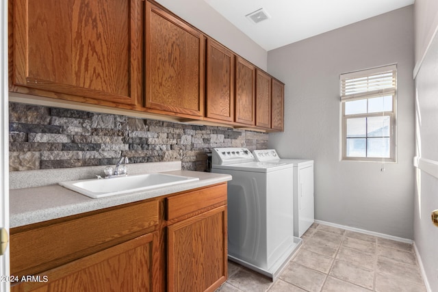 laundry area with washing machine and dryer, sink, light tile patterned floors, and cabinets