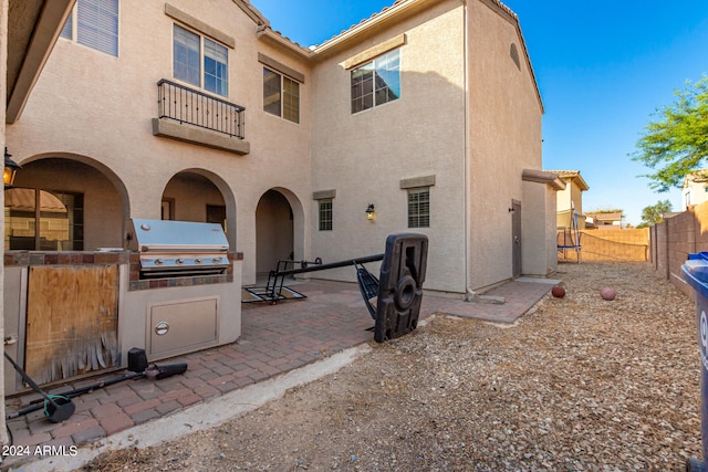 back of property featuring a balcony, an outdoor kitchen, and a patio area