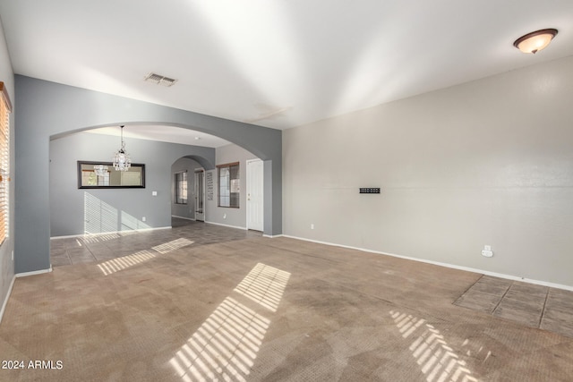 unfurnished living room featuring carpet flooring and a chandelier