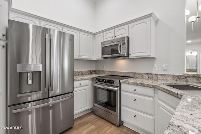 kitchen featuring light stone countertops, stainless steel appliances, white cabinetry, and light hardwood / wood-style floors