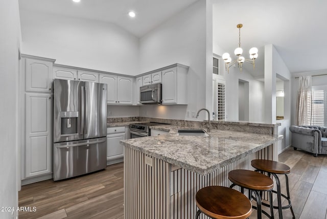 kitchen featuring sink, stainless steel appliances, dark hardwood / wood-style flooring, a notable chandelier, and kitchen peninsula