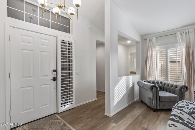 foyer with hardwood / wood-style flooring, an inviting chandelier, and lofted ceiling