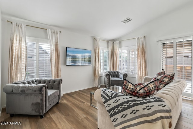 living room with a wealth of natural light, vaulted ceiling, and hardwood / wood-style flooring