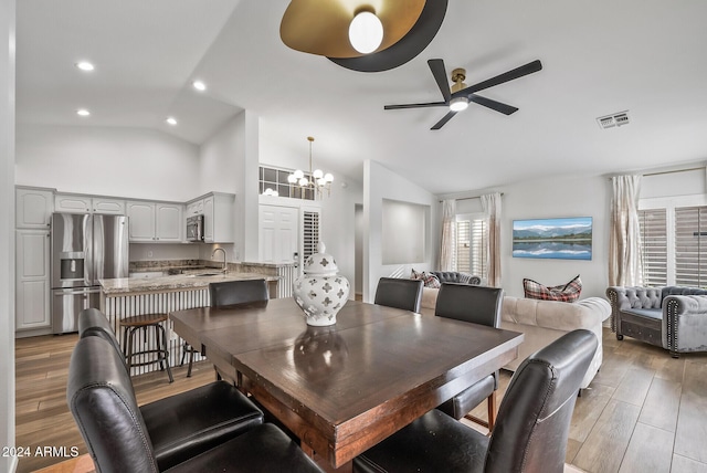 dining space with ceiling fan with notable chandelier, lofted ceiling, and sink