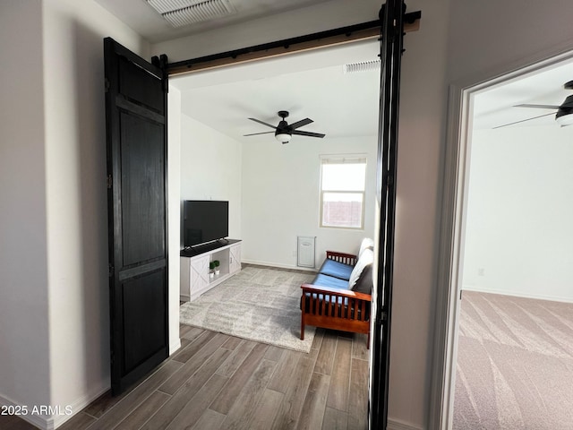 living room with ceiling fan, a barn door, and hardwood / wood-style floors