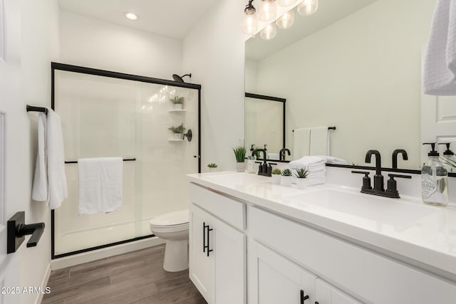 bathroom with hardwood / wood-style floors, toilet, a shower with door, and vanity