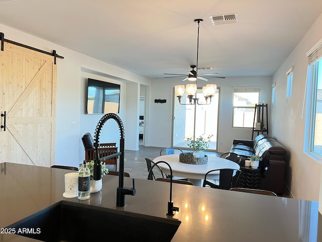 dining space with ceiling fan, a barn door, hardwood / wood-style floors, and sink