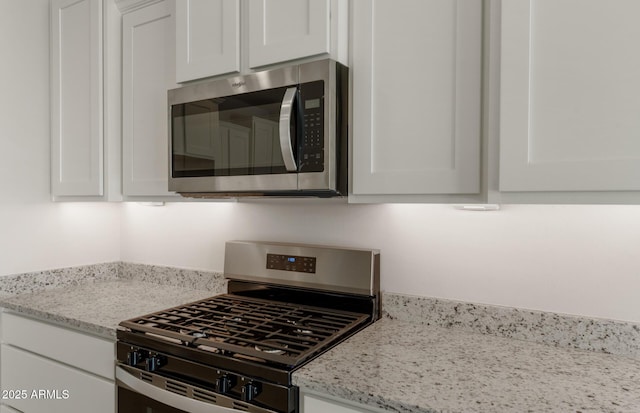 kitchen featuring light stone counters, appliances with stainless steel finishes, and white cabinetry