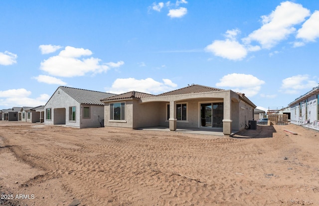 back of property with a tile roof, a patio area, and stucco siding