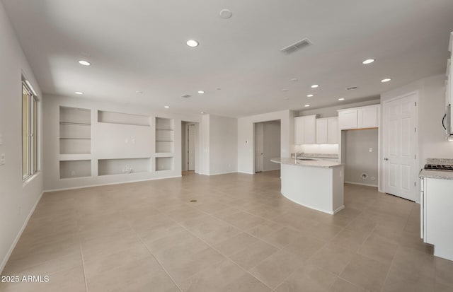 kitchen featuring a kitchen island with sink, recessed lighting, a sink, visible vents, and white cabinetry