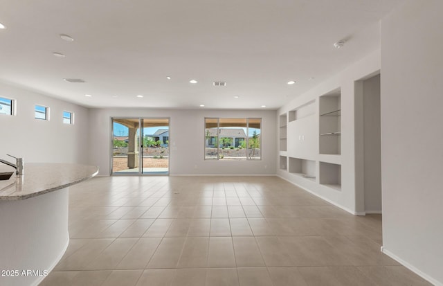 unfurnished living room with built in shelves, light tile patterned flooring, recessed lighting, and baseboards