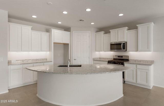 kitchen featuring stainless steel appliances, a kitchen island with sink, white cabinets, and visible vents