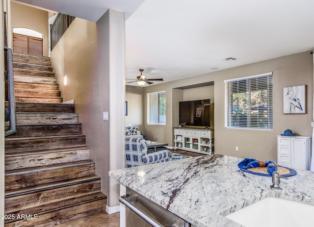 interior space with light stone counters, ceiling fan, sink, light tile patterned floors, and dishwasher