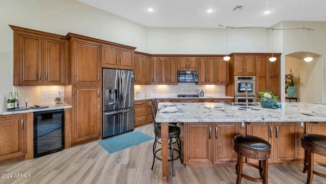 kitchen featuring light wood-type flooring, tasteful backsplash, black appliances, decorative light fixtures, and wine cooler