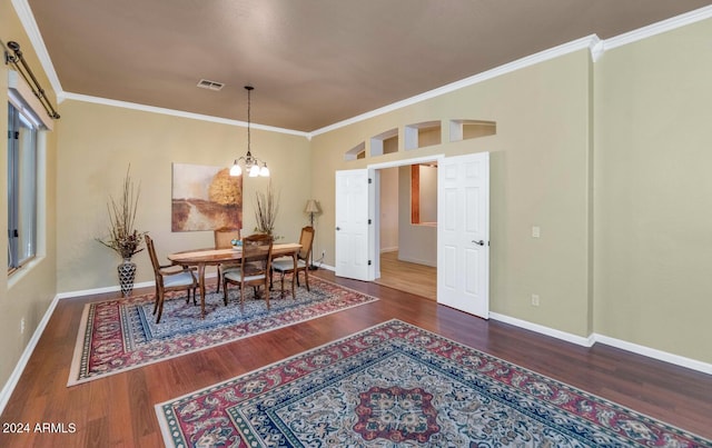 dining space featuring dark hardwood / wood-style floors, crown molding, and a notable chandelier