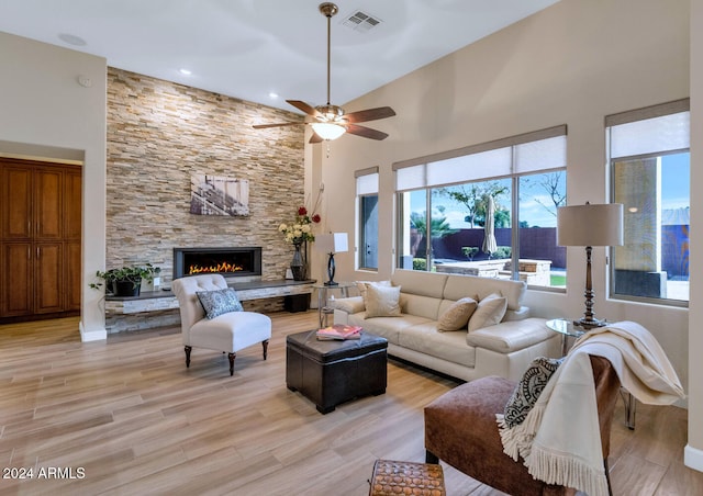 living room with ceiling fan, a fireplace, high vaulted ceiling, and light hardwood / wood-style flooring