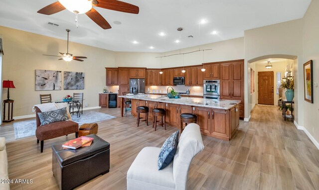 living room featuring ceiling fan, light hardwood / wood-style flooring, a towering ceiling, and beverage cooler