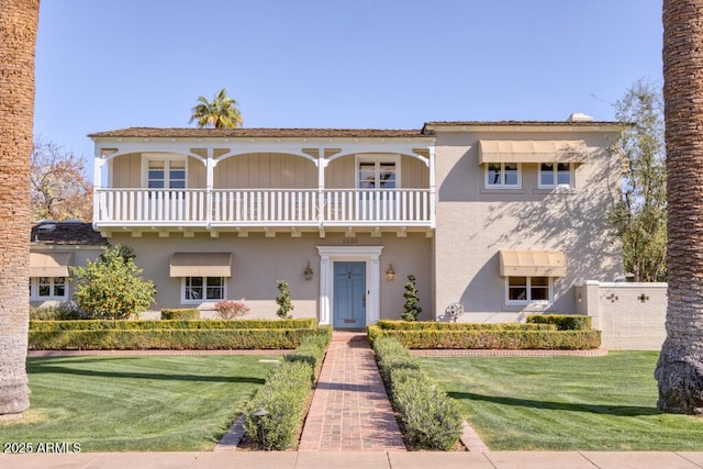 view of front of property with a balcony, stucco siding, and a front yard