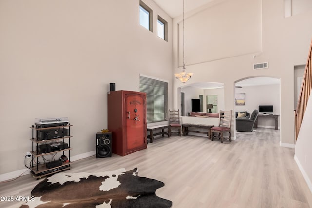 living room with a towering ceiling, hardwood / wood-style floors, and a notable chandelier