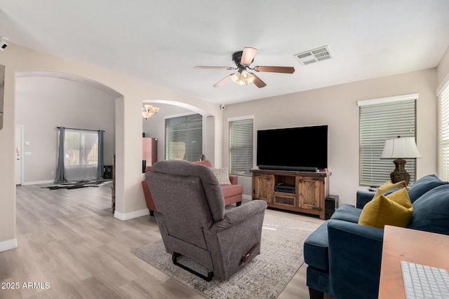 living room featuring ceiling fan with notable chandelier and light hardwood / wood-style floors