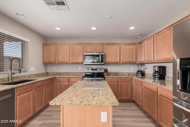 kitchen with sink, a center island, light wood-type flooring, and appliances with stainless steel finishes