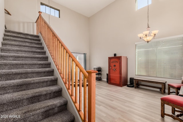 stairway featuring a high ceiling, an inviting chandelier, and wood-type flooring