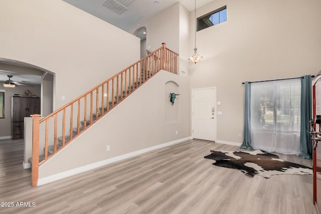 foyer with a towering ceiling, light wood-type flooring, and ceiling fan